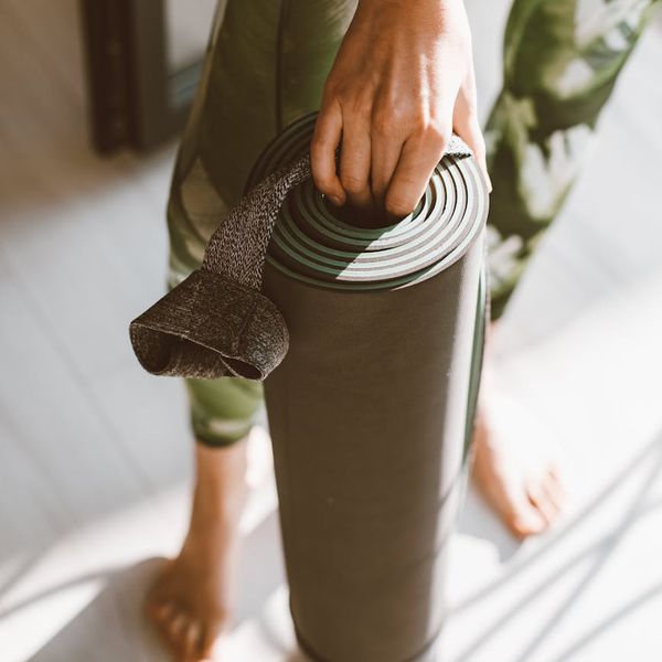 A yoga mat rolled out next to a window with morning light.
