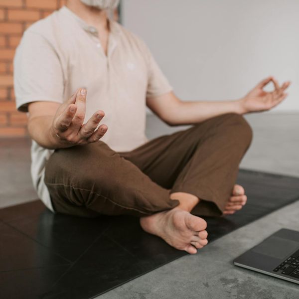 Person sitting in a meditative yoga pose in a tranquil environment.